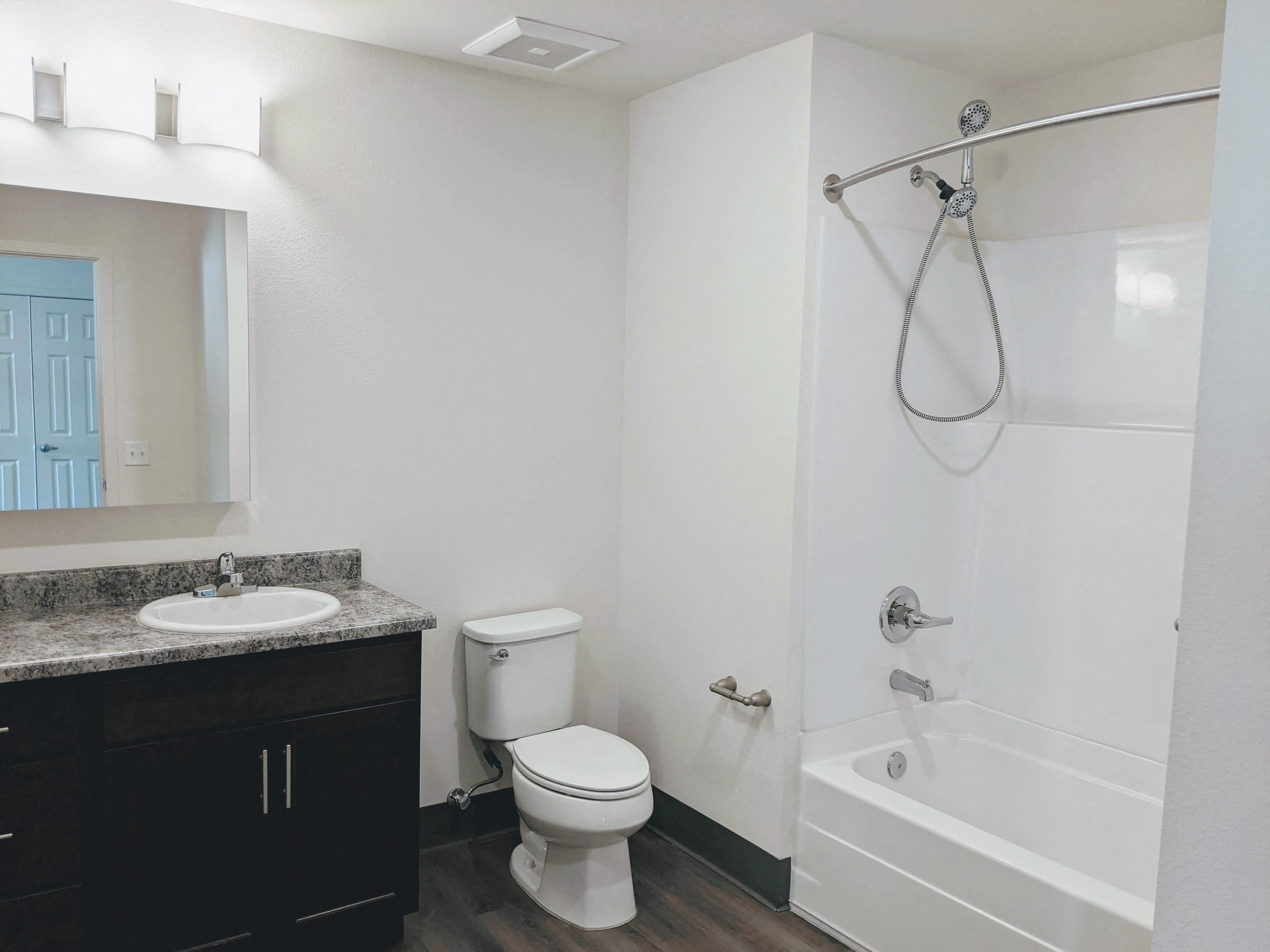 A bathroom with a tub style shower, sink, and toilet
